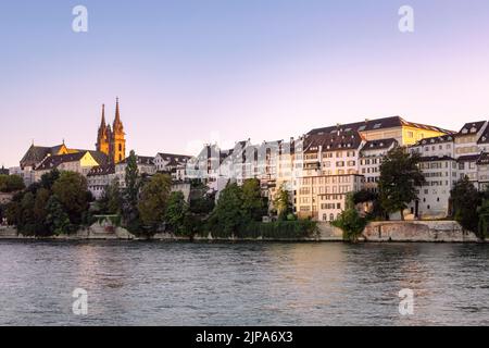 Paesaggio urbano di Basilea in Svizzera lungo il fiume Reno. Vista sull'architettura della città vecchia e sulla cattedrale di Basilea. Edifici sulla riva del fiume con luce notturna. Foto Stock