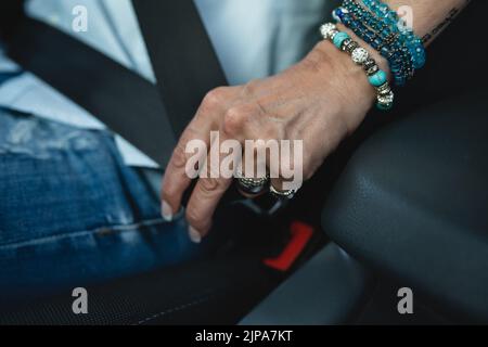 Una donna caucasica conducente seduto in auto allacciare la cintura di sicurezza tenuta con la mano guida concetto di sicurezza copia spazio selettivo focus sulle mani Foto Stock