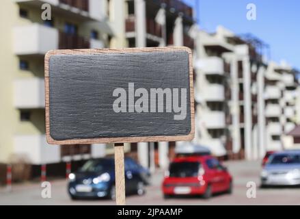 Etichetta lavagna e un edificio di appartamenti sullo sfondo, spazio copia. Foto Stock