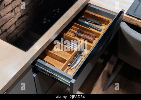 Cucina moderna. Set di posate nel cassetto della cucina. Inserti per cassetti di posate in legno massello di quercia. Foto Stock