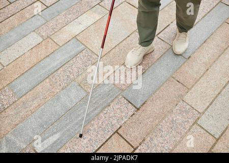 Primo piano angolare di un uomo cieco che cammina in città e usa canna sul pavimento, copia spazio Foto Stock