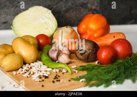 Ingredienti per cucinare il piatto nazionale ucraino - borscht. Verdure fresche sono disposte su un tagliere di legno. Preparazione per cucinare borscht. Foto Stock