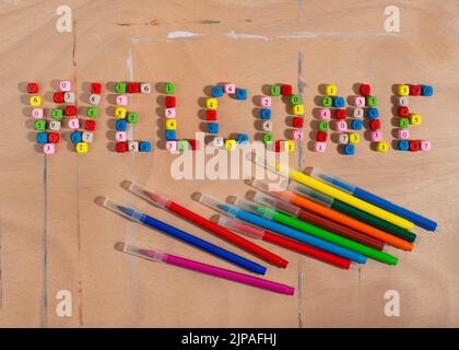 Numero perline che formano parola Benvenuto e matite su scrivania di legno. Concetto di ritorno a scuola. Foto Stock