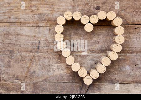 I tappi di vino formano una forma a cuore sulla tavola di legno Foto Stock