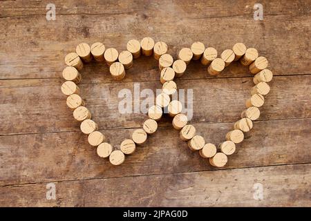 I tappi di vino formano una forma a cuore sulla tavola di legno Foto Stock