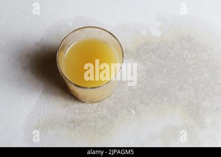 Succo d'arancia versato sulla tovaglia. Macchia grande difficile da lavare. Pulizia della cucina Foto Stock