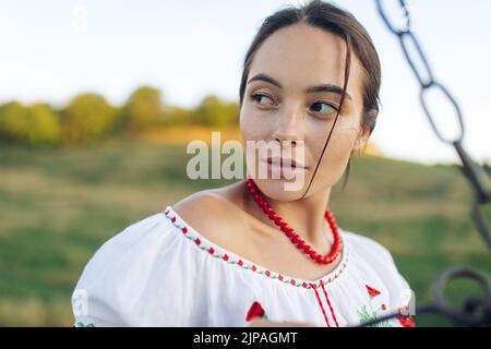 Ritratto di giovane donna Ucraina in camicia tradizionale nazionale ricamata e collana sul prato. Etnico ucraino nazionale stile abiti, ricamo Foto Stock