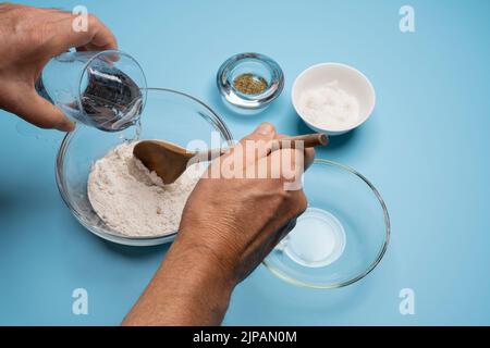 Preparazione della pizza nella cucina casalinga (passaggi da 1 a 14). Passaggio 5: Aggiungere acqua Foto Stock