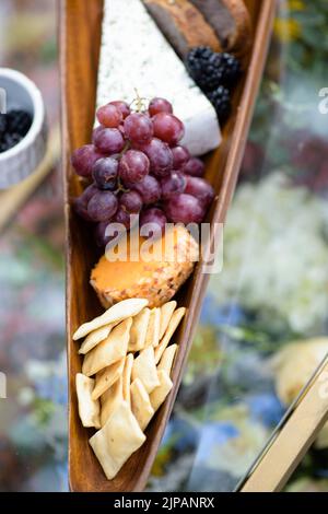 Un top shot verticale di vari tipi di formaggio e uva sul pannello di legno Foto Stock