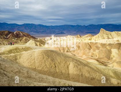 Escursionista ammirando le meraviglie naturali delle colorate Bad lands, Zabriskie Point, Death Valley National Park, California, Nord America, USA Foto Stock