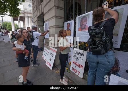 Londra, Regno Unito. 16 ago 2022. Veglia alla Casa del Sud Africa per il 10th° anniversario del massacro della miniera di platino Marikana. La polizia sudafricana ha ucciso 34 minatori. Tra i direttori della miniera della compagnia londinese Lonmin c'era Cyril Ramaphosa, ora presidente del Sudafrica. Nessuno è stato perseguito per gli omicidi. Dopo i discorsi che chiedevano giustizia e risarcimento per le famiglie operaie, la gente ha registrato le immagini dei morti e dei fiori alle porte dell'edificio. Peter Marshall/Alamy Live News Foto Stock