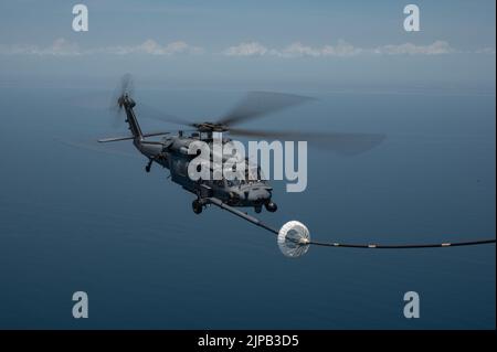 Un elicottero HH-60G Pave Hawk viene rifornito da un 39th Rescue Squadron HC-130J Combat King II durante una gara di tiro al tacchino al largo della costa della Florida il 16 giugno 2022. Durante il concorso, i membri dell'equipaggio hanno gareggiato su abilità come l'impiego di armi da aerei, il rifornimento di aerei da elicotteri, la navigazione degradata, la ricerca degradata e il sollevamento confinato. (STATI UNITI Foto forza spaziale di Senior Airman Thomas Sjoberg) Foto Stock