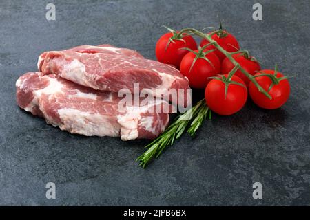 Carne cruda con pomodori su una superficie nera Foto Stock