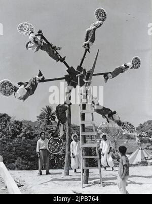 Fotografia in bianco e nero dei ballerini Totonac chiamati Voladores (Fliers) indossando costumi tradizionali con elaborati headdress circolari che eseguono un antico rituale che coinvolge una grande ruota di legno, Messico (probabilmente lo stato di Veracruz) Foto Stock