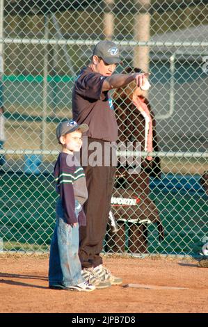 Giovani e allenatori su campi sportivi durante gli sport primaverili, allenati e giocati, partite di baseball Foto Stock