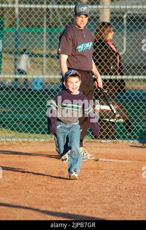 Giovani e allenatori su campi sportivi durante gli sport primaverili, allenati e giocati, partite di baseball Foto Stock