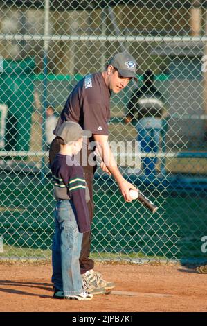 Giovani e allenatori su campi sportivi durante gli sport primaverili, allenati e giocati, partite di baseball Foto Stock