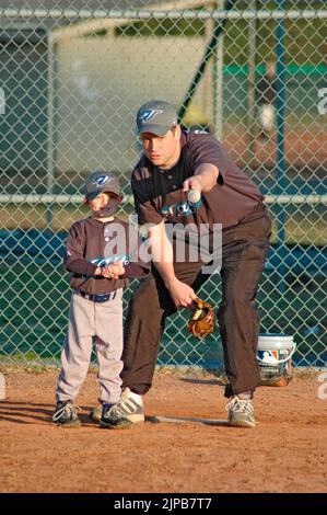 Giovani e allenatori su campi sportivi durante gli sport primaverili, allenati e giocati, partite di baseball Foto Stock