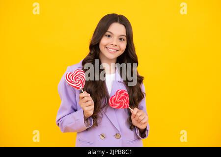 Bambino teen freddo con lollipop sopra sfondo isolato giallo. Dolce vita d'infanzia. Ragazza teen con caramella lollipop yummy. Felice adolescente, positivo e. Foto Stock