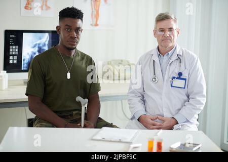 Ritratto dell'ex soldato con canna accanto al suo medico generico e guardando la macchina fotografica Foto Stock