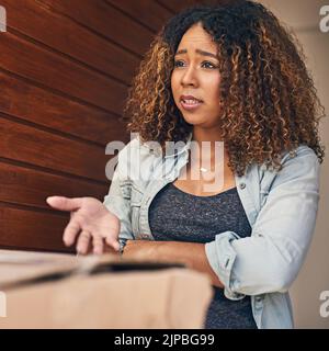 Questo non è quello che ho ordinato. Una giovane donna che guarda turbato mentre riceve una consegna dal corriere. Foto Stock