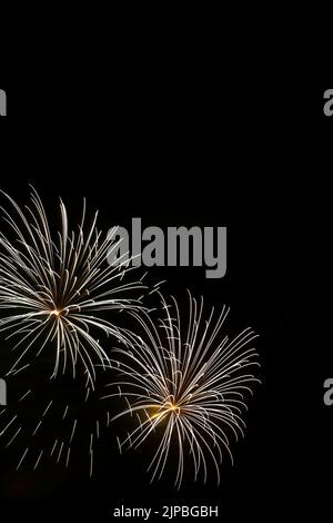 Fuochi d'artificio bianchi e gialli nel cielo notturno. Foto Stock