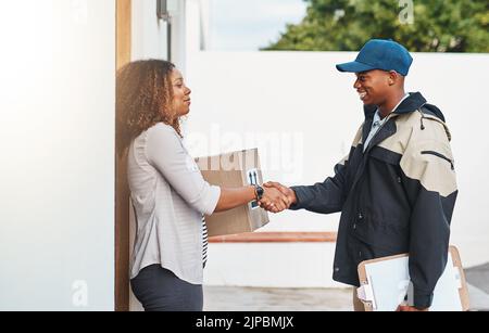 Il vostro servizio non delude mai. Un corriere che scuote le mani con un cliente mentre fa una consegna. Foto Stock