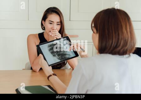 Una paziente di sesso femminile sta ascoltando il medico spiegare dopo una radiografia. Foto Stock