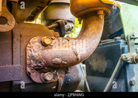 Primo piano tubo di scarico del fornello arrugginito di un trattore con cabina di guida collegato a un motore del trattore con cabina di guida. Riparazione e restauro di macchine agricole Foto Stock