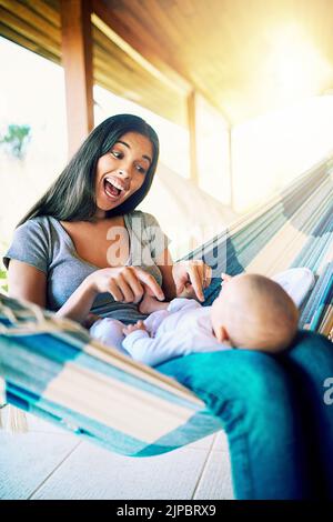 WOS il ragazzino più intelligente del mondo. Una giovane madre allegra che si rilassa su un'amaca con il figlio appena nato fuori casa durante il giorno. Foto Stock