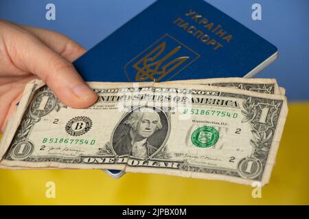 La mano di una donna tiene un passaporto straniero e dollari sullo sfondo della bandiera dell'Ucraina, migrazione e viaggi Foto Stock