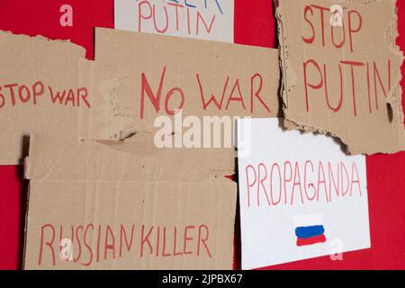 Cartelloni con slogan per fermare la guerra, l’assassino russo, la propaganda, l’assassino Putin, fermare Putin, nessuna guerra su sfondo rosso, azione di protesta 2022 Foto Stock