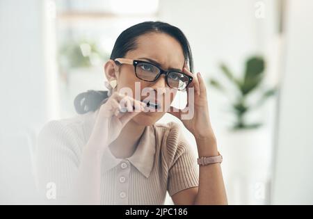 Donna d'affari seria, pensante e confusa mordendo la penna, sentendosi nervosa e cercando di risolvere un problema. Professionista di affari femminile che lotta Foto Stock