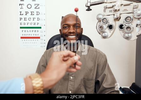 Uomo nero che ha gli occhi testati ad un optometro. Sorridente afroamericano che si consulta con un opthamologist, avendo una visione e cura degli occhi Foto Stock