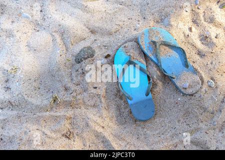 Vacanze estive in spiaggia, infradito blu nella sabbia in una località turistica sul Mar Baltico in Germania, copia spazio, focus selezionato, angolo alto vi Foto Stock