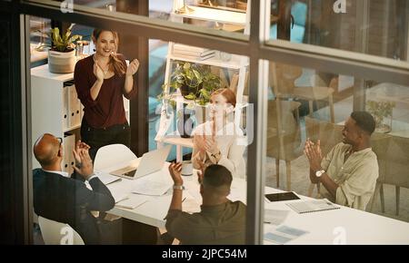 Il team di successo batte le mani, allietando durante un affare o una riunione in un ufficio moderno. Gruppo diversificato motivato da un piano, un obiettivo o una strategia. Colleghi con Foto Stock