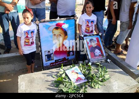 Jabalia, striscia di Gaza, Palestina. 16th ago, 2022. Gaza, Palestina. 16 agosto 2022. I palestinesi tengono una veglia nel cimitero di al Fallujah vicino al campo profughi di Jabalia nella striscia di Gaza settentrionale. I bambini tenevano striscioni che chiedevano la protezione dei bambini, nel sito dove 5 bambini della famiglia Najm sono stati uccisi nell'ultima offensiva israeliana su Gaza. La veglia segue un'ammissione da parte di funzionari israeliani che cinque bambini sono stati uccisi in un attacco aereo israeliano contro il cimitero di al-Fallujah ad ovest del campo profughi di Jabalia nella striscia di Gaza settentrionale il 7th agosto (Credit Image: © Ahmad Hasaballah Foto Stock