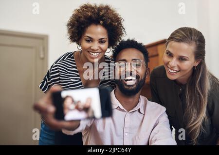 Diversi, divertenti e felici uomini d'affari che prendono un selfie su un telefono in un ufficio insieme. Sorridente gruppo di colleghi e amici che si legano, ridendo e. Foto Stock