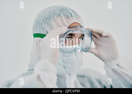 Operatore sanitario che indossa tuta protettiva di nocciola durante l'epidemia di virus cocvido. Professionista di ricerca medica in una zona di quarantena che si prepara per Foto Stock