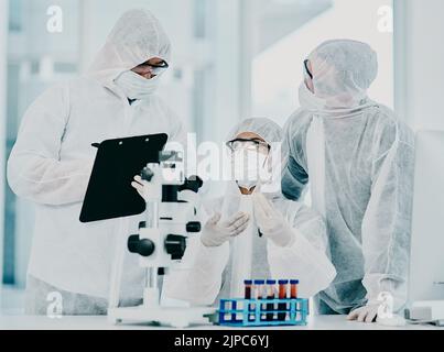 Scienza e medici di ricerca che lavorano sul vaccino covid test mentre indossano tute di protezione in medicina moderna laboratorio. Gruppo di Foto Stock