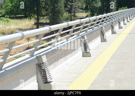 una recinzione metallica di protezione su un lato della strada Foto Stock