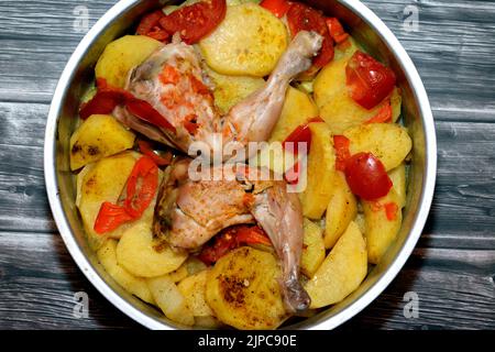 Cosce e cosce di pollo con fette di patate, pomodori e cipolle con spezie al curry cotte nel forno in un vassoio, fuoco selettivo di cibo egiziano c Foto Stock