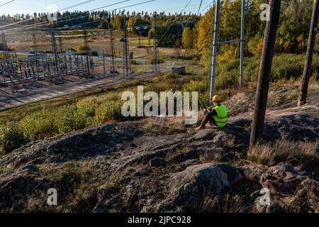 Vista aerea intorno a un ingegnere, seduto e leggendo i dati di utilizzo dalla centrale elettrica sul suo pad Foto Stock