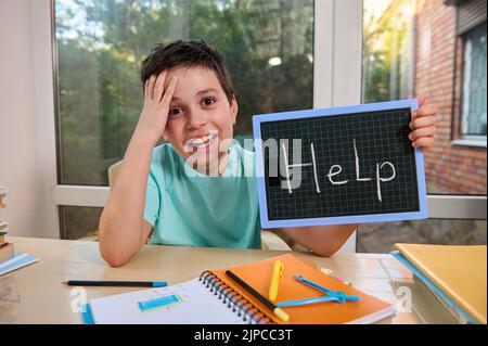 Schoolboy perplesso tiene una lavagna, chiede aiuto per risolvere problemi di matematica e geometria. Difficoltà di apprendimento Foto Stock