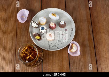 Piccolo bicchiere di cioccolato con crema di pistacchio, accanto a macaron, tartufi, cameo di noce e bicchiere di whiskey. Foto Stock