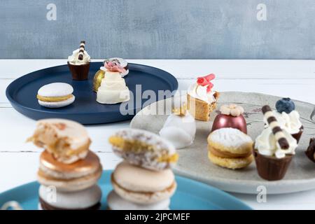 Piccola torta al cioccolato bianco accanto a dolci assortiti. In primo piano sfocato, macaron impilati. Foto Stock