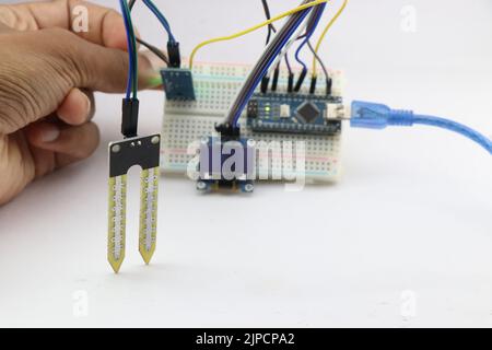 Progetto digitale di misuratore di umidità del suolo realizzato a casa utilizzando un microcontroller e alcuni altri componenti elettronici assemblati su un circuito breadboard Foto Stock