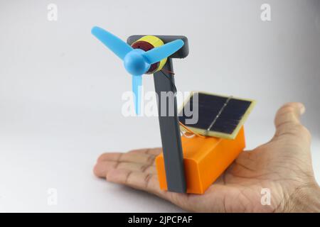 Pannelli solari ad assorbimento di energia solare che alimentano una piccola ventola collegata a un motore c.c. tenuto in mano Foto Stock