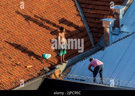 Marilia, Sao Paulo, Brasile, 29 luglio 2022. Vista dall'alto di un lavoratore che mette lamiere su una casa per ristrutturare il tetto di un punto commerciale della città Foto Stock