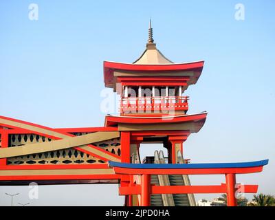 Un ponte pedonale rifinito in tradizionale stile architettonico giapponese, il ponte è servito con scale elettriche e di colore rosso, in stile giapponese b Foto Stock